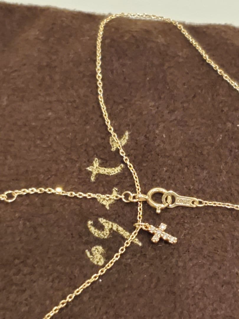 Agete gold necklace with a detailed cross motif pendant on a fine gold chain