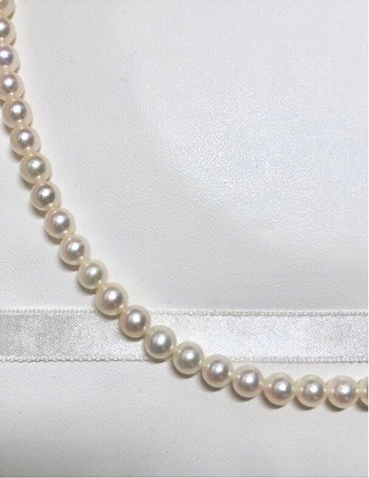 Akoya pearl necklace with round white pearls 5.5-6.0mm and silver clasp on a white background