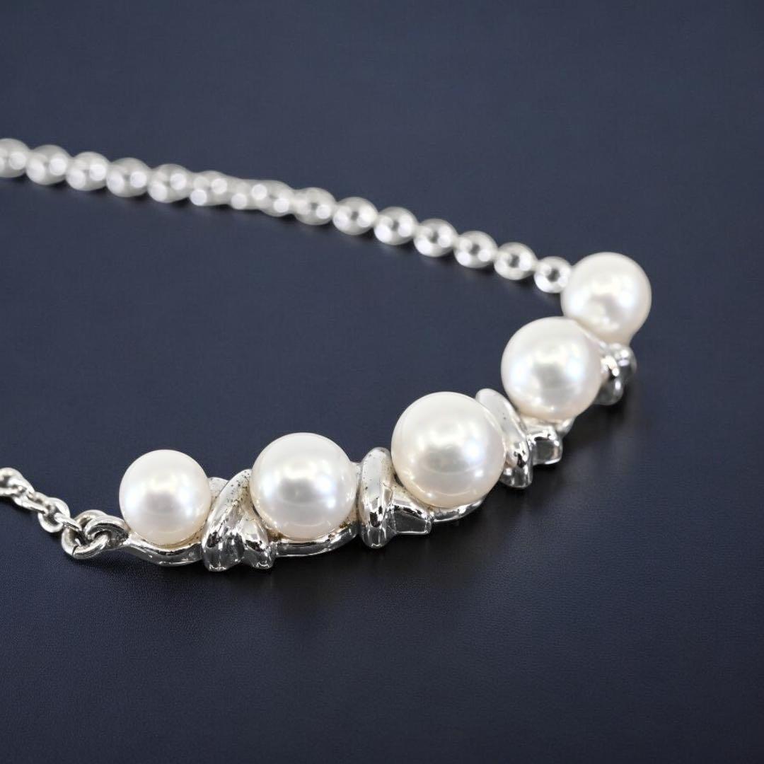 Tasaki Akoya pearl necklace pendant with round genuine pearls and silver clasp on a white background