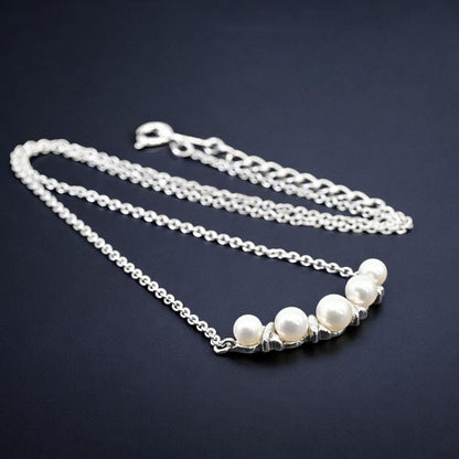 Tasaki Akoya pearl necklace pendant with round genuine pearls and silver clasp on a white background
