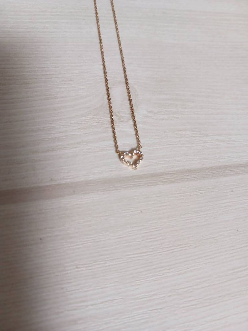 Close-up of pink gold necklace featuring an open heart-shaped agate stone with small diamonds