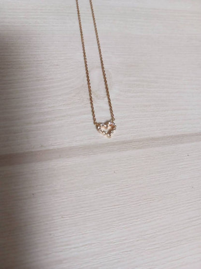 Close-up of pink gold necklace featuring an open heart-shaped agate stone with small diamonds