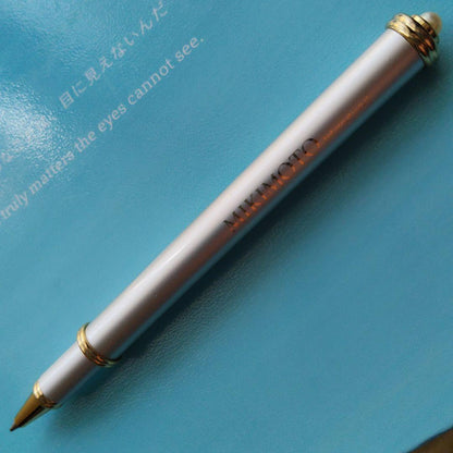 Mikimoto pendant head with decorative pearls, non-working watch, and ballpoint pen set on white background