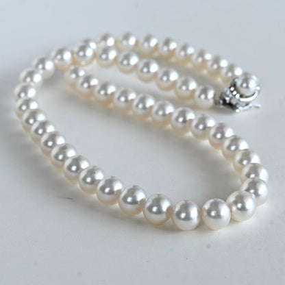 Hanadama Akoya pearl necklace with round 8-8.5mm pearls and silver fastener on a white background