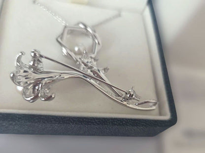 TASAKI pearl necklace with 6mm pearls and silver flower motif brooch set on white background
