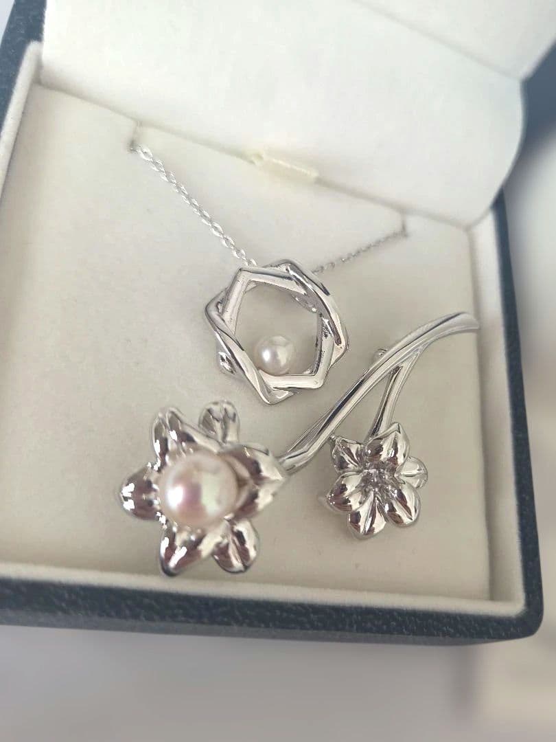 TASAKI pearl necklace with 6mm pearls and silver flower motif brooch set on white background