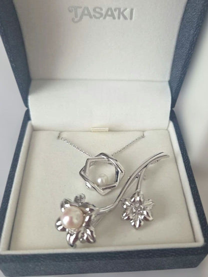 TASAKI pearl necklace with 6mm pearls and silver flower motif brooch set on white background