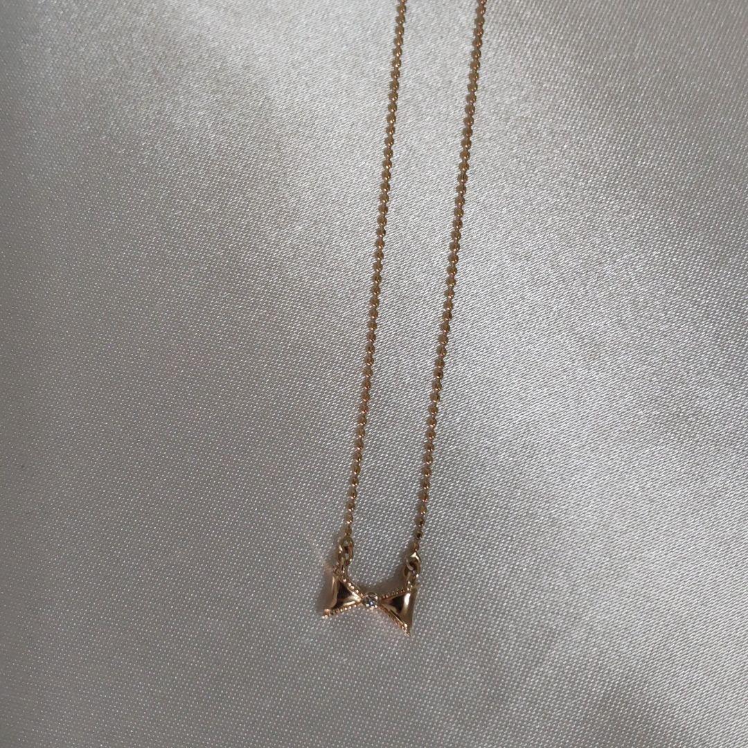 Beautiful agete ribbon-shaped necklace made of pink gold displayed on a white background