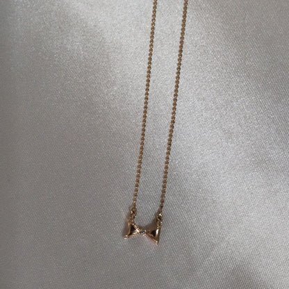 Beautiful agete ribbon-shaped necklace made of pink gold displayed on a white background