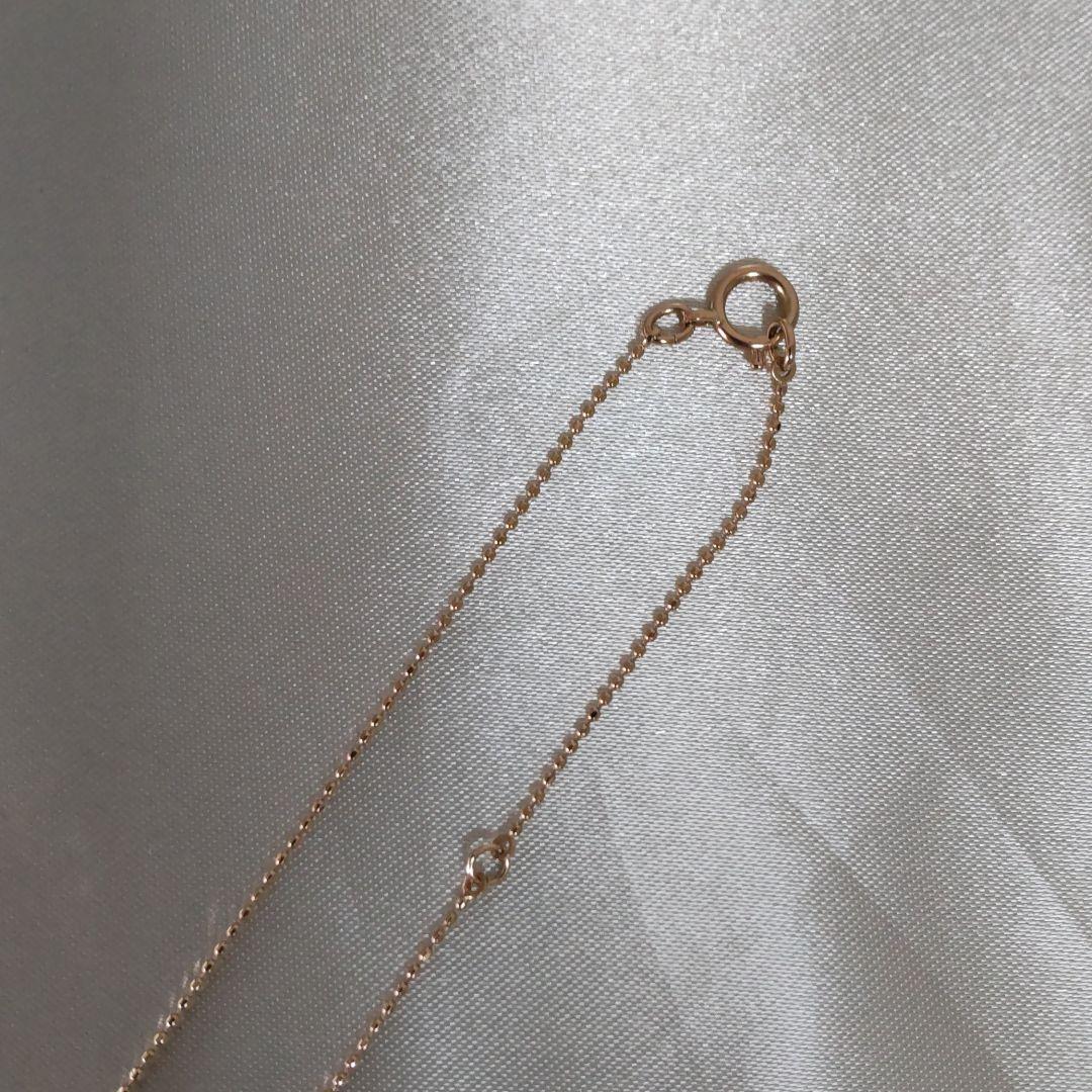 Beautiful agete ribbon-shaped necklace made of pink gold displayed on a white background