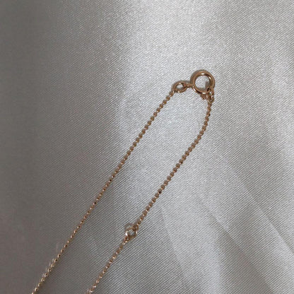 Beautiful agete ribbon-shaped necklace made of pink gold displayed on a white background