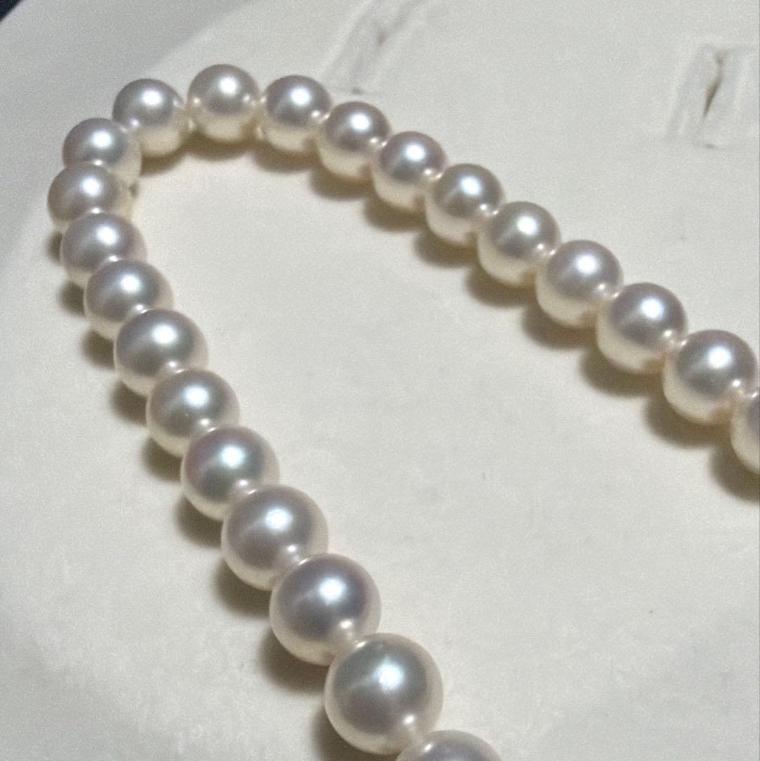MIKIMOTO Akoya Pearl Necklace with 7.5 natural pearls and high luster on a white background