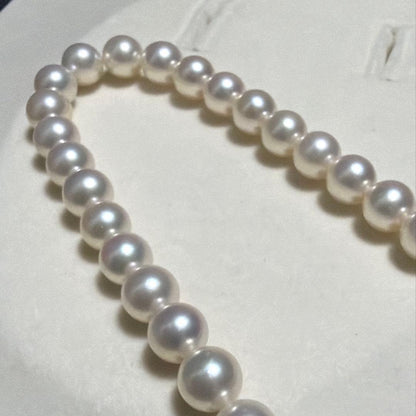 MIKIMOTO Akoya Pearl Necklace with 7.5 natural pearls and high luster on a white background