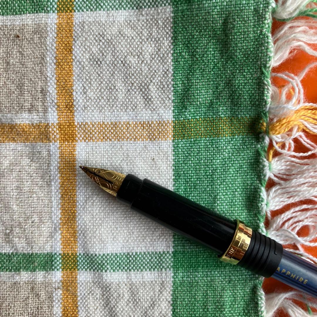 Cross black matte ballpoint pen with silver accents next to Parker blue and black fountain pen with gold nib engraving 88