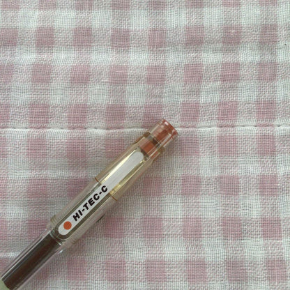 Pilot Hi-Tech C ballpoint pen in fluorescent brown with visible signs of wear and discoloration