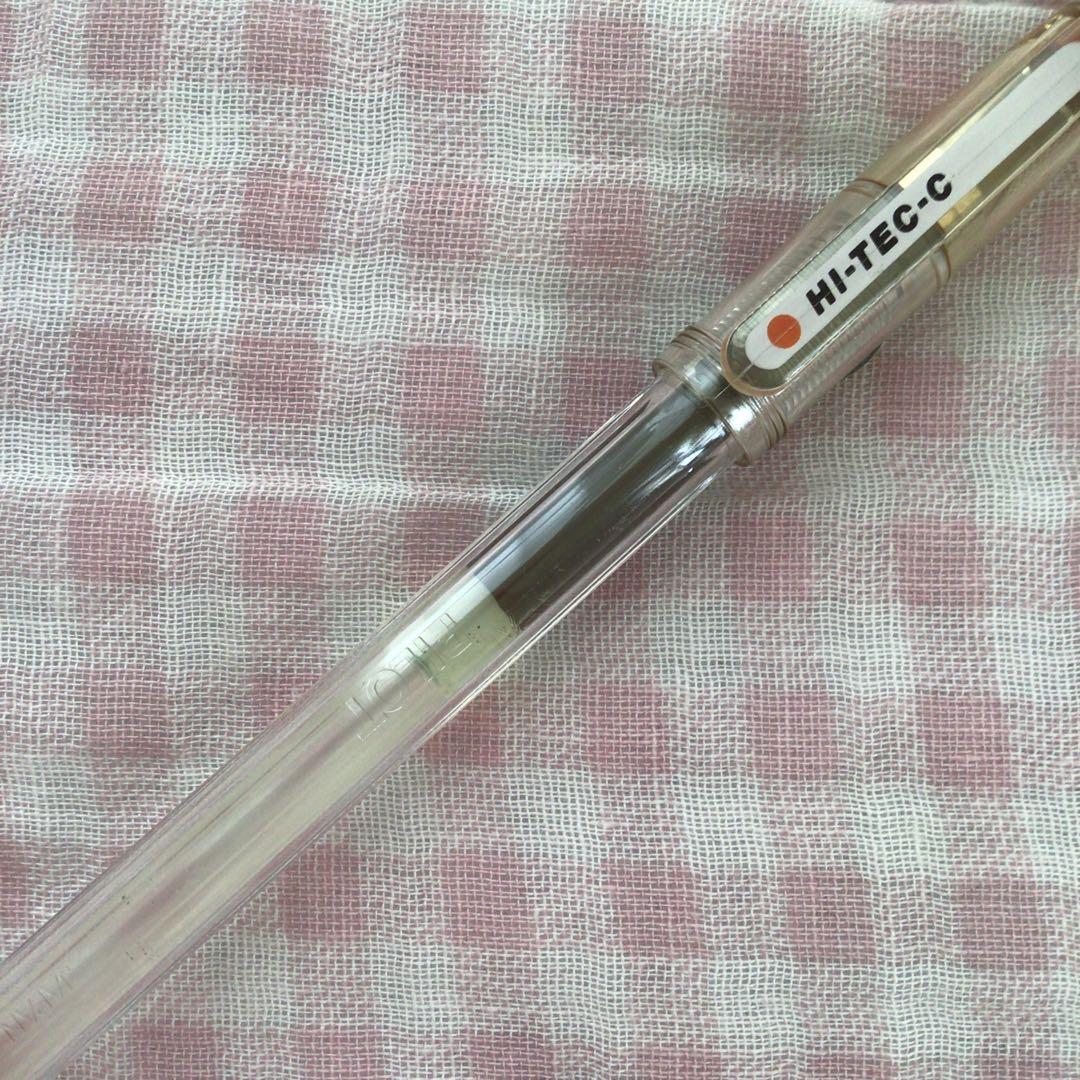 Pilot Hi-Tech C ballpoint pen in fluorescent brown with visible signs of wear and discoloration