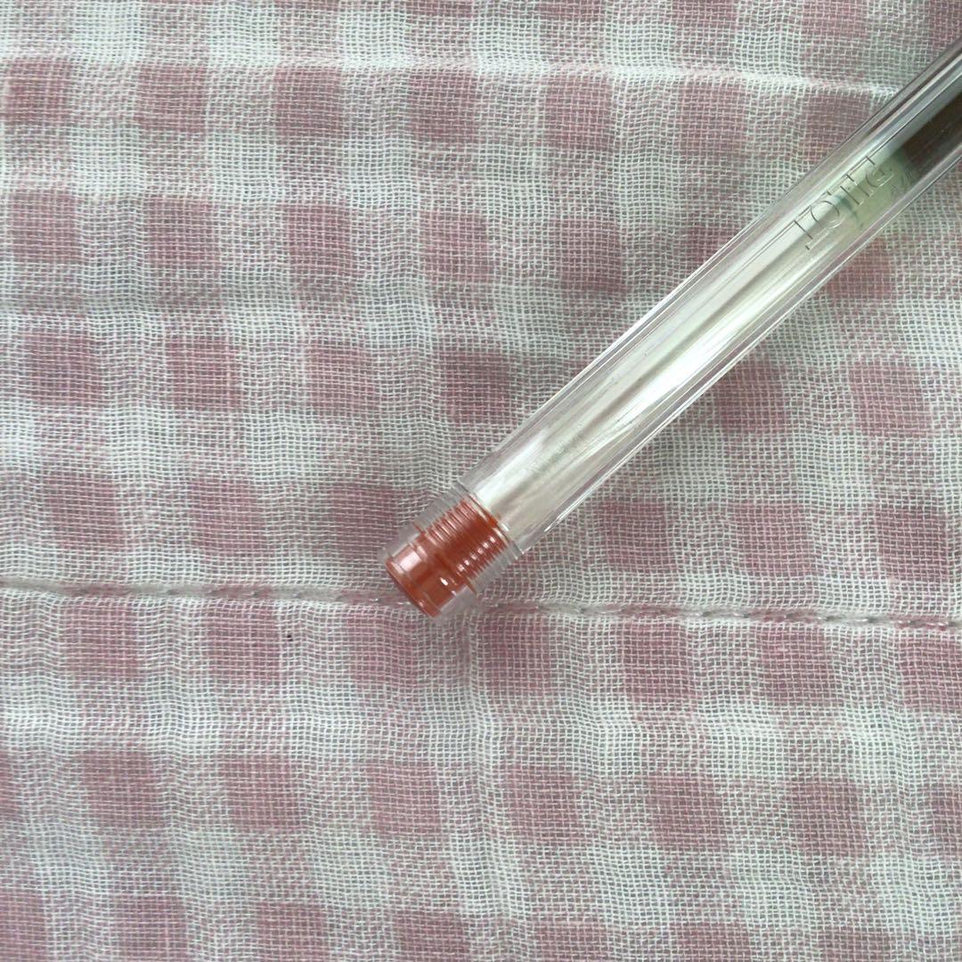 Pilot Hi-Tech C ballpoint pen in fluorescent brown with visible signs of wear and discoloration