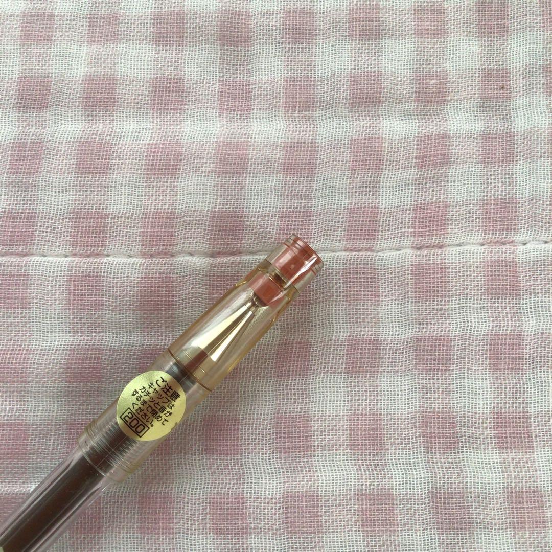 Pilot Hi-Tech C ballpoint pen in fluorescent brown with visible signs of wear and discoloration