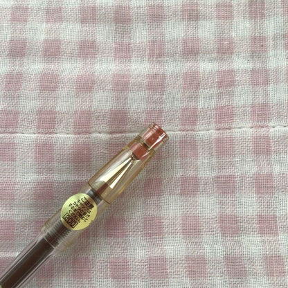 Pilot Hi-Tech C ballpoint pen in fluorescent brown with visible signs of wear and discoloration