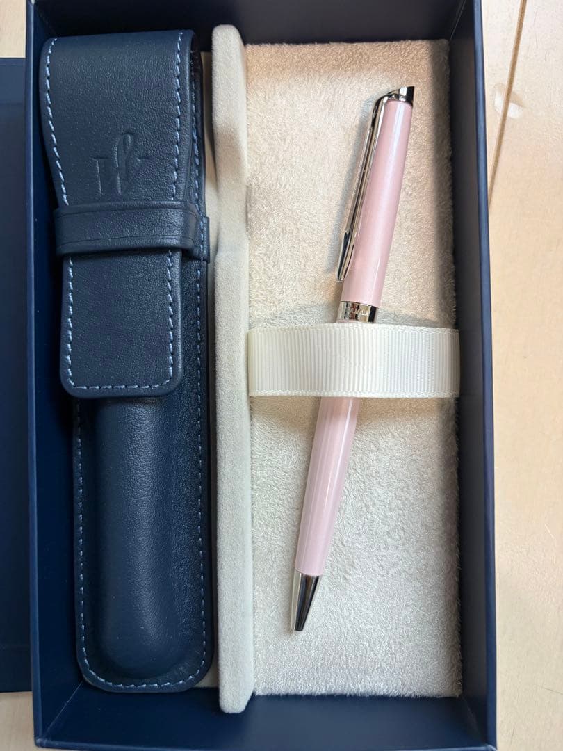 WATERMAN ballpoint pen with light pink body and twist mechanism next to its dedicated leather case