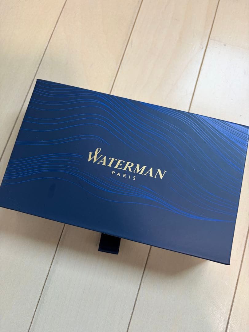 WATERMAN ballpoint pen with light pink body and twist mechanism next to its dedicated leather case