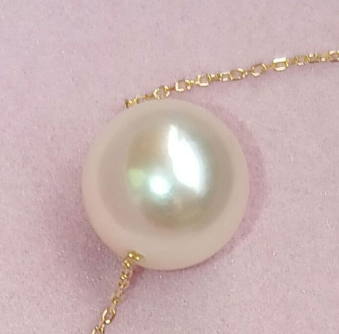 Akoya pearl pendant with 18 karat gold setting and 38cm chain on white background