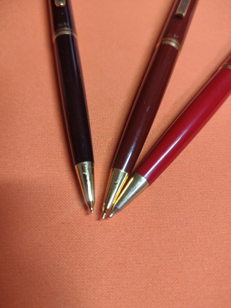 Three Pilot mechanical pencils in red and assorted colors, including used and unused items