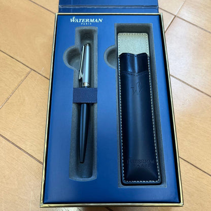 Waterman black metal ballpoint pen with accompanying brown leather case on white background