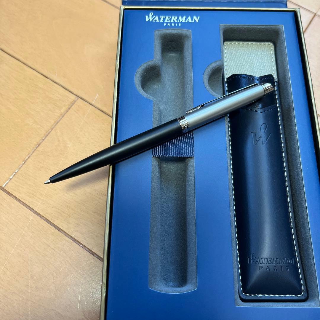 Waterman black metal ballpoint pen with accompanying brown leather case on white background