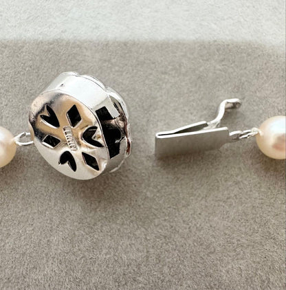 Akoya pearl necklace with 7mm pearls, silver clasp with inscription, displayed with certificate and case