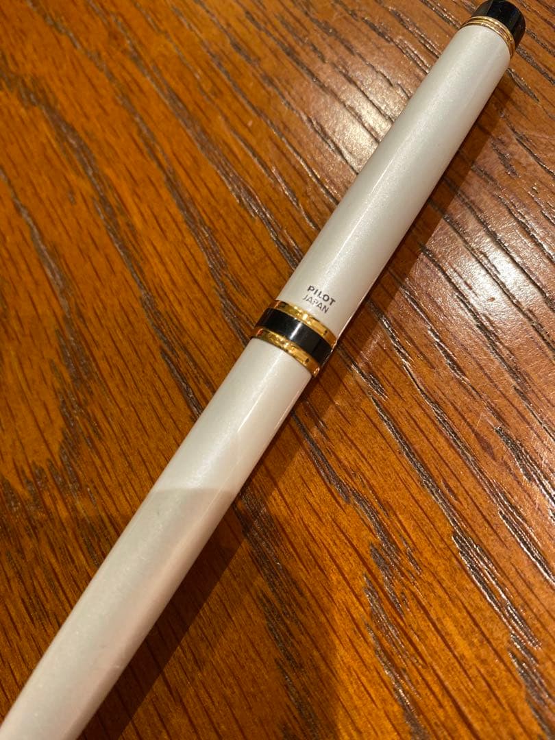 Pilot ballpoint pen with white metal body, gold trim, and blue top shown on a white background