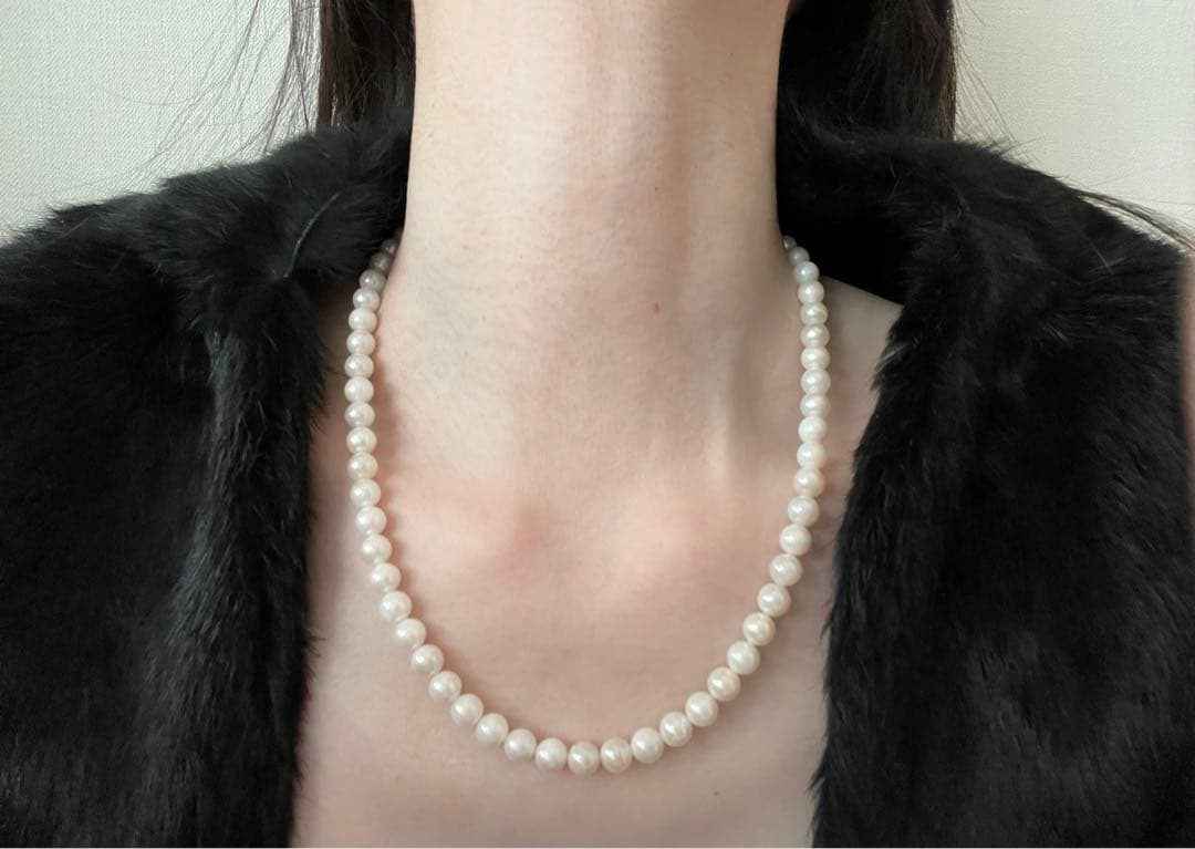 Akoya pearl necklace, earrings, and pendant set with white round pearls and silver chains on white background