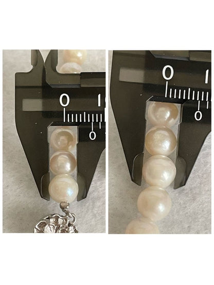 Akoya pearl necklace, earrings, and pendant set with white round pearls and silver chains on white background