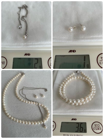Akoya pearl necklace, earrings, and pendant set with white round pearls and silver chains on white background