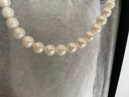 Akoya pearl necklace, earrings, and pendant set with white round pearls and silver chains on white background