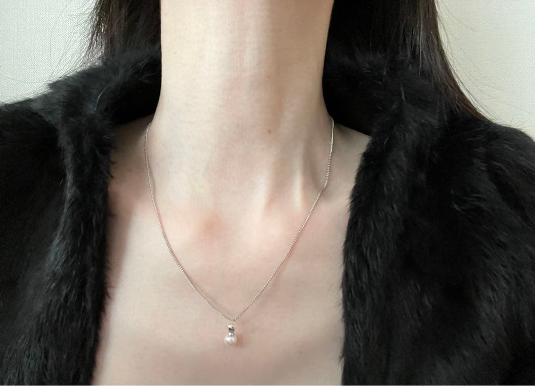 Akoya pearl necklace, earrings, and pendant set with white round pearls and silver chains on white background