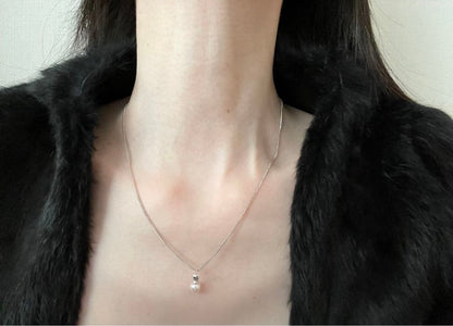 Akoya pearl necklace, earrings, and pendant set with white round pearls and silver chains on white background