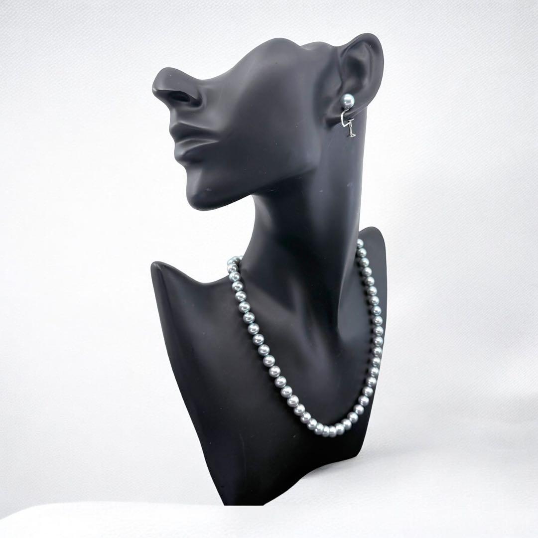 Tasaki Akoya pearl necklace and earrings set with 7mm round pearls and silver clasp on white background