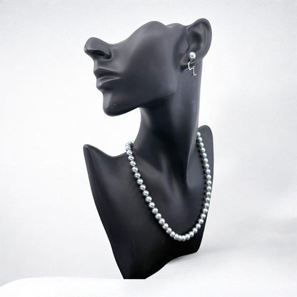 Tasaki Akoya pearl necklace and earrings set with 7mm round pearls and silver clasp on white background