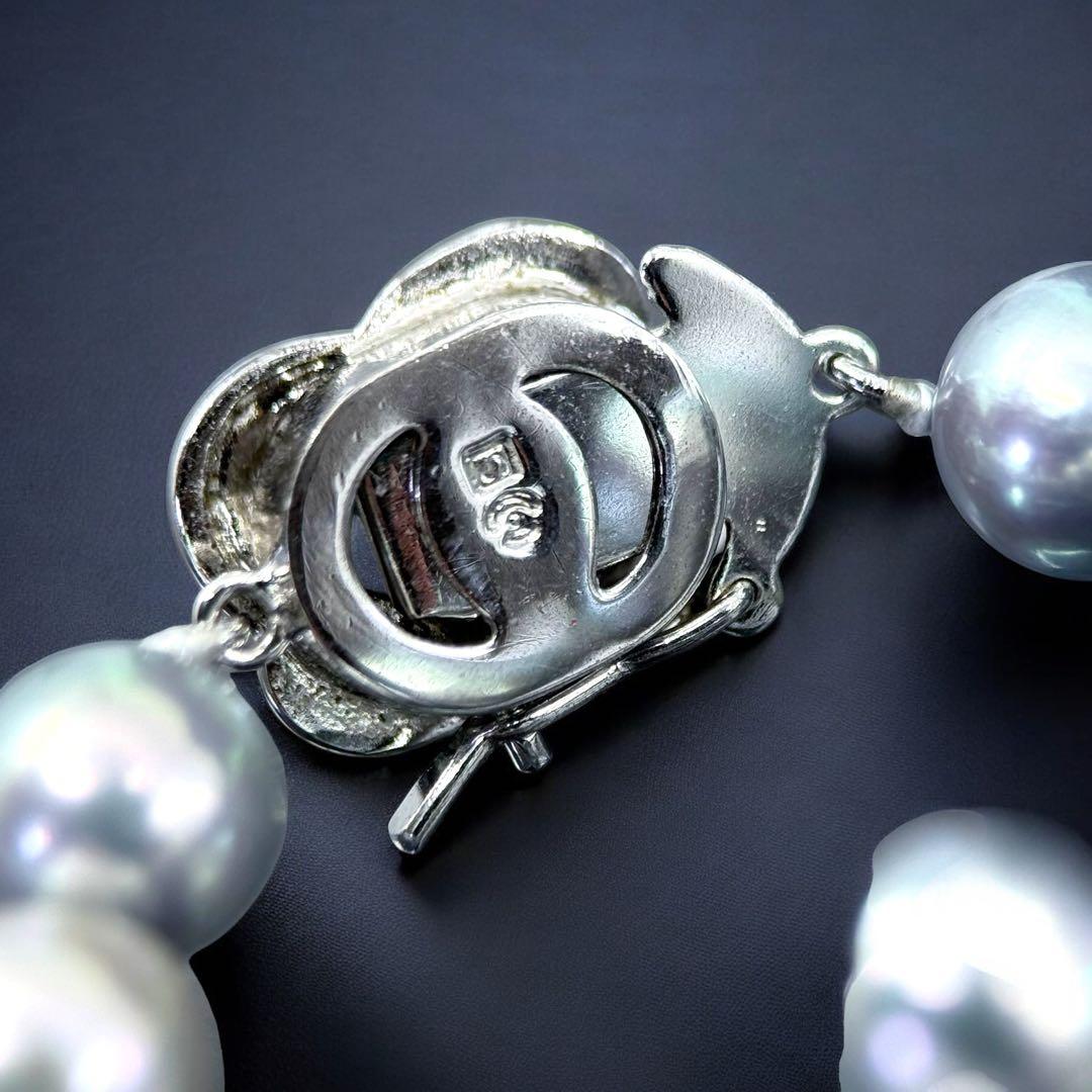 Tasaki Akoya pearl necklace and earrings set with 7mm round pearls and silver clasp on white background