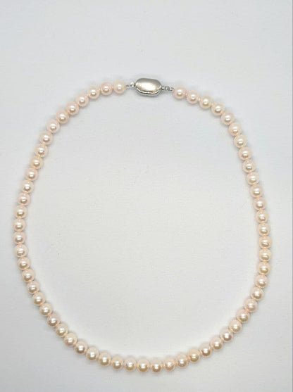 Close-up of an Akoya pearl necklace with 6.5-7mm pearls and a sterling silver clasp on a white background