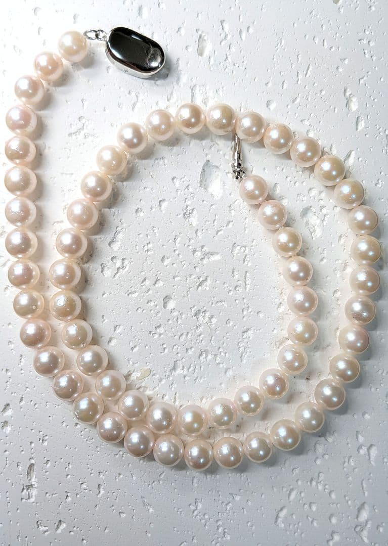 Close-up of an Akoya pearl necklace with 6.5-7mm pearls and a sterling silver clasp on a white background
