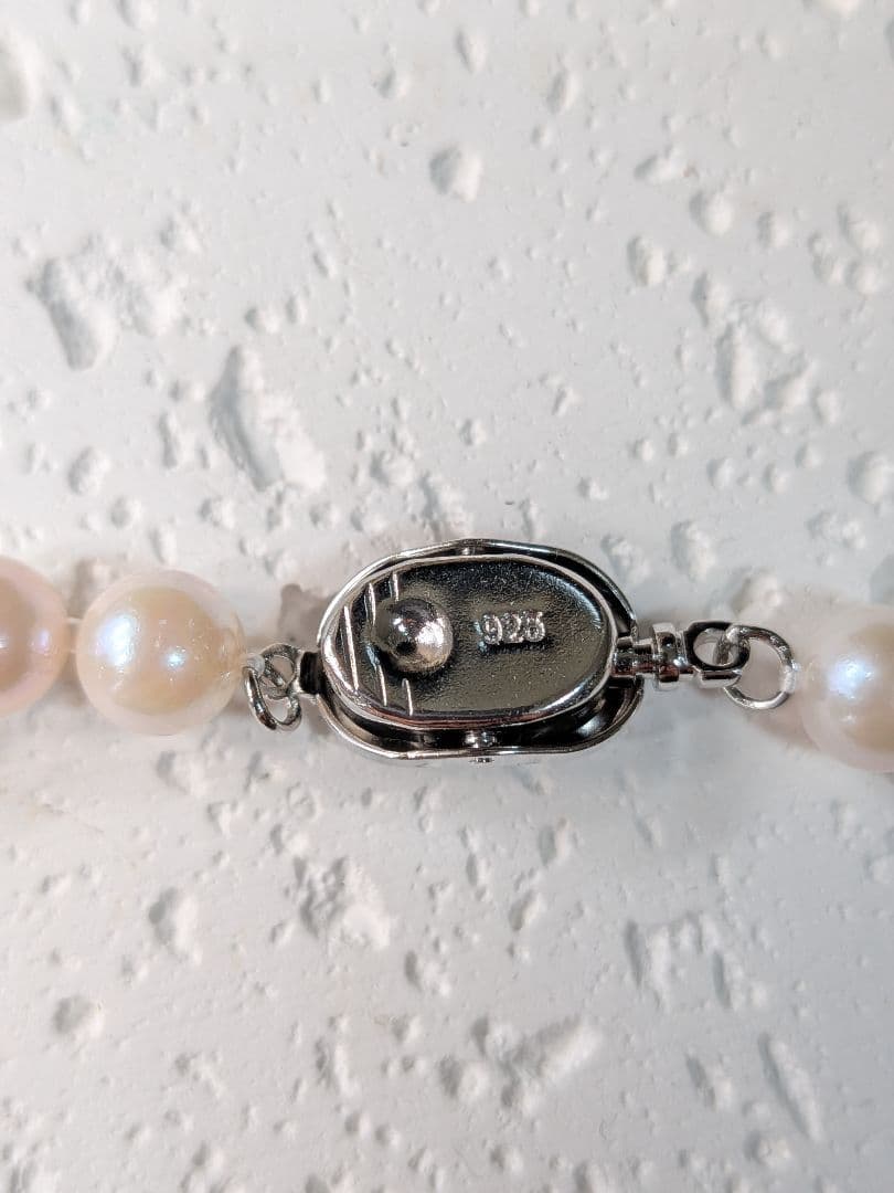 Close-up of an Akoya pearl necklace with 6.5-7mm pearls and a sterling silver clasp on a white background