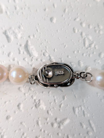 Close-up of an Akoya pearl necklace with 6.5-7mm pearls and a sterling silver clasp on a white background