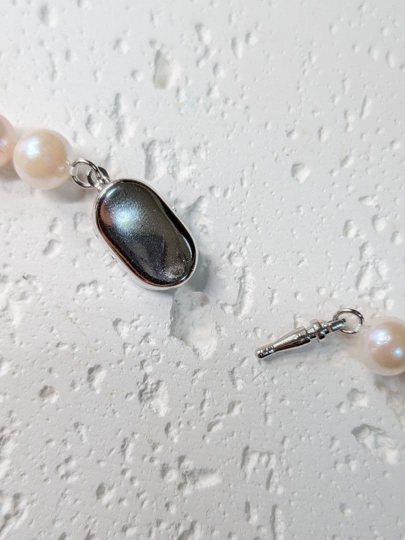 Close-up of an Akoya pearl necklace with 6.5-7mm pearls and a sterling silver clasp on a white background