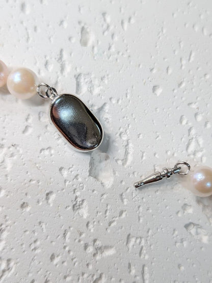 Close-up of an Akoya pearl necklace with 6.5-7mm pearls and a sterling silver clasp on a white background