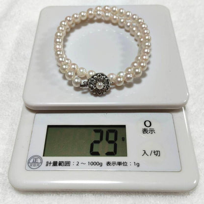 Akoya pearl necklace with 4-7mm white pearls and silver stamp clasp on a white background