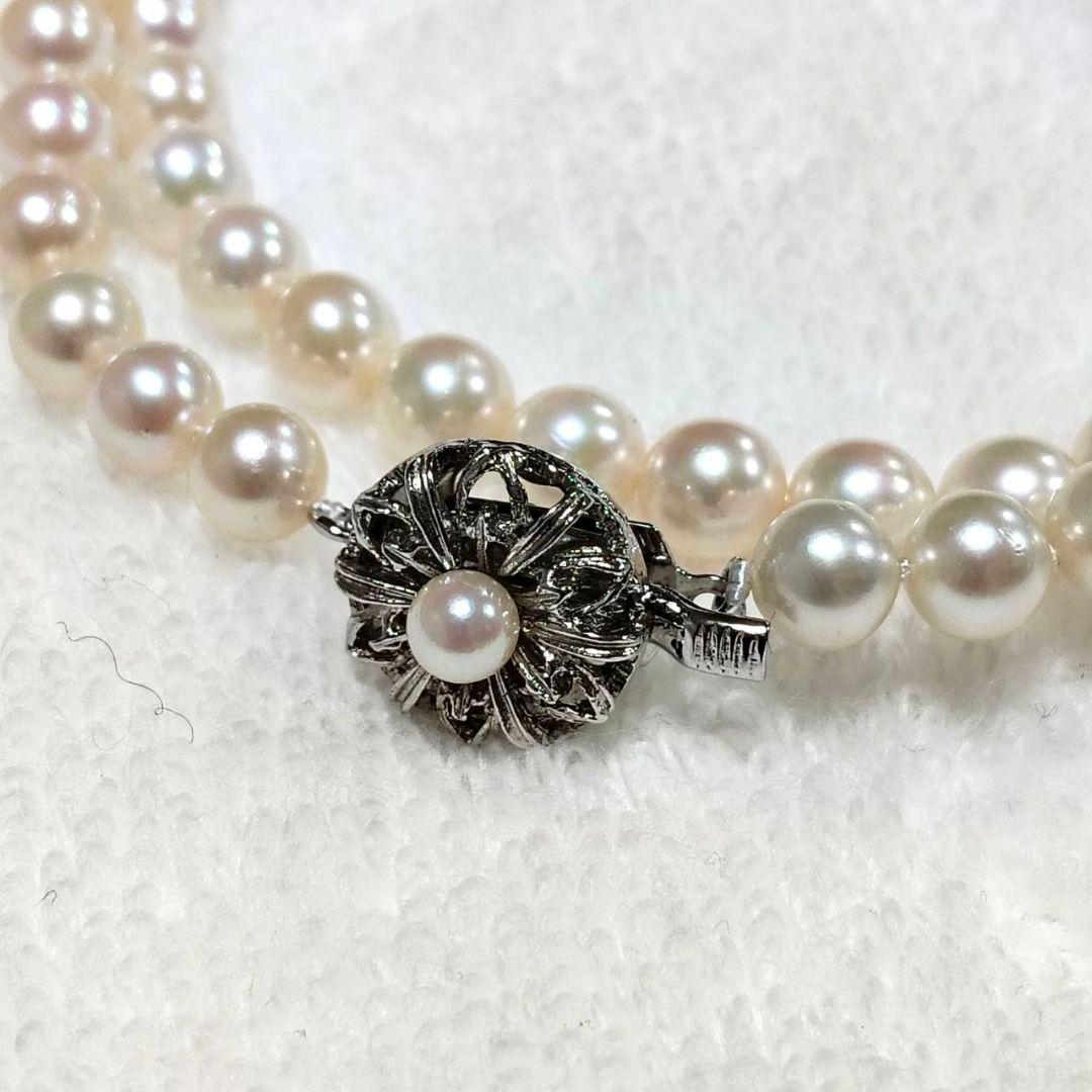 Akoya pearl necklace with 4-7mm white pearls and silver stamp clasp on a white background