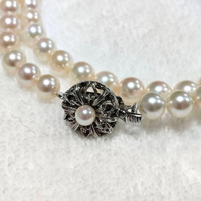 Akoya pearl necklace with 4-7mm white pearls and silver stamp clasp on a white background