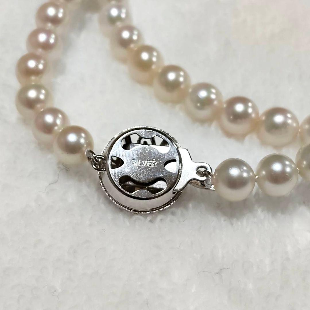 Akoya pearl necklace with 4-7mm white pearls and silver stamp clasp on a white background